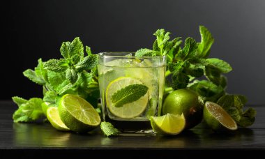 Siyah ahşap bir masada buzlu, limonlu ve naneli mojito..