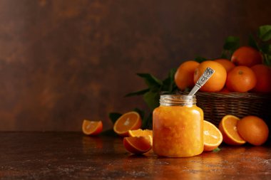 Cam kavanozda portakal reçeli ve kahverengi şarap masasında taze meyve. Boşluğu kopyala.