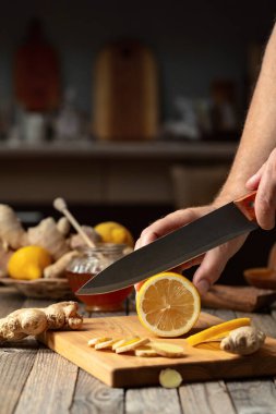 Adam limon kesti. Mutfak masasında zencefil çayı hazırlamak için gerekli malzemeler..