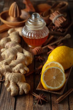 Zencefilli çay hazırlamak için gerekli malzemeler. Zencefil, limon, bal, anason ve tarçın çubukları eski bir mutfak masasında..