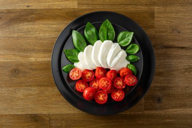 Eski ahşap bir masada fesleğen ve kiraz domatesli Mozzarella. Kopyalama alanı olan üst görünüm.