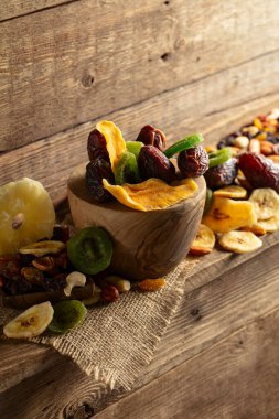 Kurumuş tropikal meyveler, çeşitli fındıklar ve kuru üzümler eski ahşap bir masada..