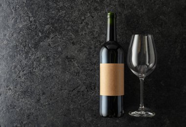 Siyah taştan bir arka planda bir şişe kırmızı şarap. Boşluğu kopyala.