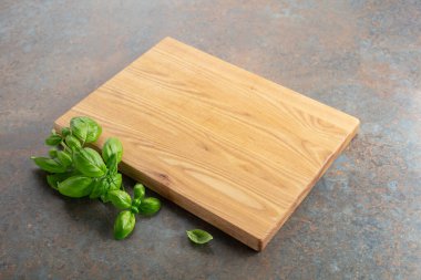 Mutfak masasında tahta ve fesleğen kesiyorum. Mutfak geçmişi. Boş tahta kesme tahtası, ürün görüntüleme alanı.