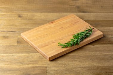 Tahta kesme tahtası ve biberiye eski ahşap bir masada. Mutfak geçmişi. Boş tahta kesme tahtası, ürün görüntüleme alanı.