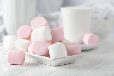 Beyaz ahşap bir masada pembe ve beyaz şekerlemeler..