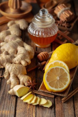 Zencefilli çay hazırlamak için gerekli malzemeler. Zencefil, limon, bal, anason ve tarçın çubukları eski bir mutfak masasında..