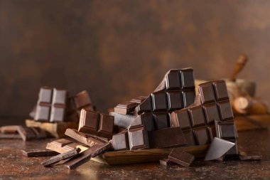 Kahverengi bir arka planda kırık acı ve sütlü çikolatalar..