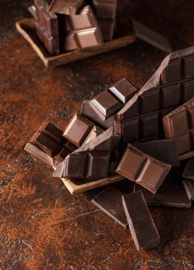 Kahverengi bir arka planda kırık acı ve sütlü çikolatalar..