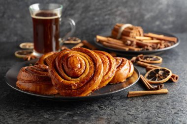 Kanelbullar - İsveç tarçınlı çörekler ya da dürümler. Siyah taş bir masada taze pişmiş çörekler..