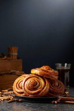 Kanelbullar - İsveç tarçınlı çörekler ya da dürümler. Siyah arka planda taze pişmiş çörekler. Boşluğu kopyala.