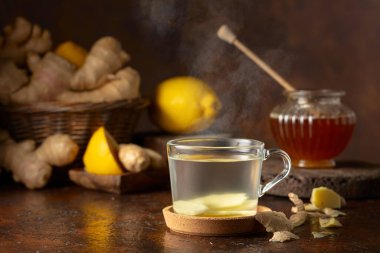 Kahverengi arka planda limonlu ve ballı zencefil çayı.