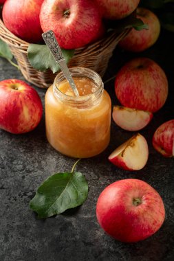 Elma reçeli ve kırmızı taze elmalar siyah taş bir masada..