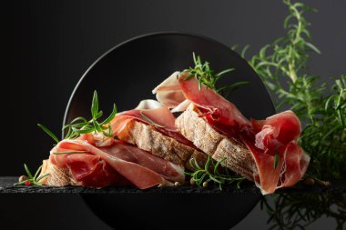 Siyah arka planda prosciutto ve biberiyeli Ciabatta. Geleneksel İtalyan atıştırması.