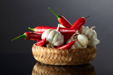 Siyah yansıtıcı arka planda sarımsak soğanları ve kırmızı biberler..