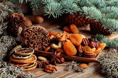Eski ahşap bir masada kurumuş meyve ve fındık. Kurutulmuş turunçgiller, kayısılar, kuru üzümler, çeşitli fındıklar, tarçın çubukları ve anason içeren bir Noel..
