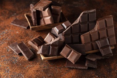 Kahverengi bir arka planda kırık acı ve sütlü çikolatalar..