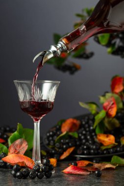 Böğürtlen likörü şişeden bardağa dökülür. Tatlı bir içecek ve siyah taş bir masada taze böğürtlen.