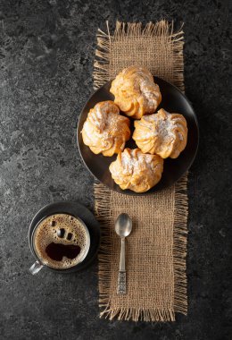 Kremalı kek ve sade kahve siyah taş bir masada. Üst görünüm.