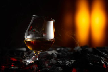 Yanan bir kömürün üzerinde bir fırt brendi. Sert alkollü içecekler kavramı. Boşluğu kopyala.