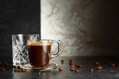 Siyah taş bir masada espresso ve bir bardak soğuk su. Boşluğu kopyala.