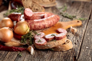 Kurutulmuş sosis, kekik, soğan, sarımsak ve biber. Eski ahşap bir masada sosis ve baharat..