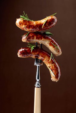 Biberiyeli ızgara Bavyera sosisi. Biberiye serpilmiş çatallı sosisler. Kahverengi arkaplan.