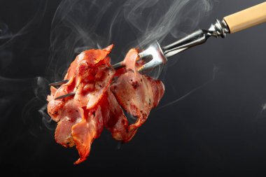 Siyah arka planda kızarmış pastırma dilimleri. Kızarmış domuz pastırması. Boşluğu kopyala.