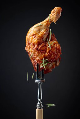 Siyah arka planda biberiye serpilmiş ızgara tavuk budu. Çataldaki tavuk budu..