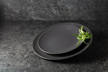 Siyah taşlı arka planda biberiyeli boş siyah tabaklar. Ürününüzü bir tabağa koyun.