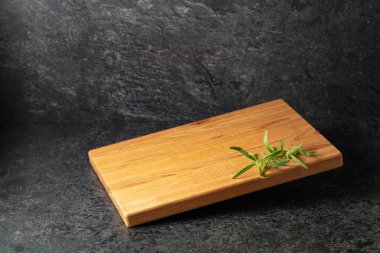 Siyah taşlı arka planda biberiyeli boş kesim tahtası. Boşluğu kopyala.