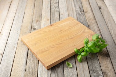 Tahta ve fesleğeni eski ahşap mutfak masasında kesiyorum. Mutfak geçmişi. Boş tahta kesme tahtası, ürün görüntüleme alanı.