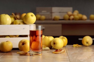 Fresh juicy apples in in wooden box and glass of apple juice on a kitchen table. clipart