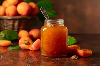 Cam kavanozda kayısı reçeli ve kahverengi bir masada taze meyve. Boşluğu kopyala.