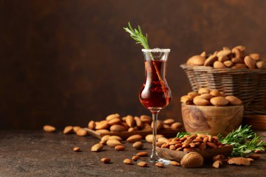 Alkolik İtalyan likörü Amaretto. Şarap masasında badem fıstığı var. Boşluğu kopyala.