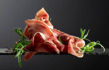 Siyah arka planda biberiyeli Prosciutto Crudo. Boşluğu kopyala.