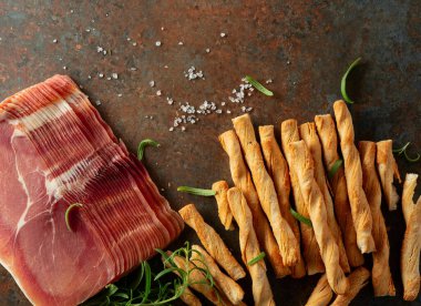 Ekmek çubuğu ve paslı arka planda biberiyeli Prosciutto. Üst görünüm.