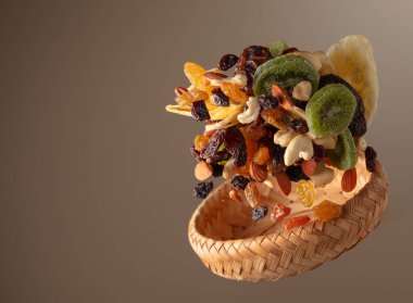 Çeşitli fındıklı kurutulmuş tropikal meyveler ve bej arka planda hareketli kuru üzümler. Boşluğu kopyala.