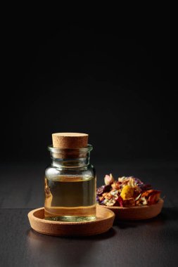 Temel yağ ya da cam şişedeki bitkisel tentür. Siyah arka planda kurutulmuş sağlıklı şifalı bitkiler ve şifalı bitkilerin karışımı. Boşluğu kopyala.