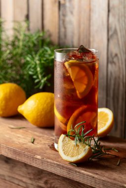 Buzlu çay ya da eski ahşap bir masada buzlu, biberiyeli ve limon dilimli alkollü kokteyl. Taze, sağlıklı, soğuk limon suyu. Buzlu ve limonlu çay..