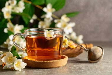 Bir fincan yasemin çayı ve taş bir masada taze yasemin çiçekleri. Boşluğu kopyala.