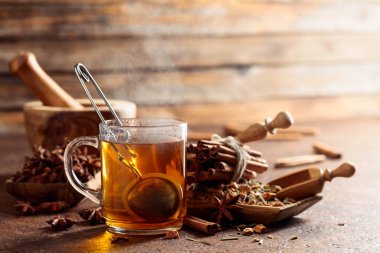 Tarçınlı, anasonlu ve kurutulmuş bitkisel çay. Eski kahverengi bir masada, ahşap tabaklarda baharatlı bitki çayı. Boşluğu kopyala.