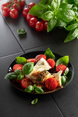 Fesleğenli Mozzarella, vişneli domates ve üzerine Akdeniz baharatları serpiştirilmiş pesto sosu. Geleneksel İtalyan mutfağı.