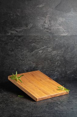 Siyah taşlı arka planda biberiyeli boş kesim tahtası. Boşluğu kopyala.