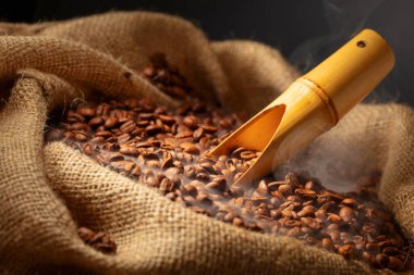 Taze kavrulmuş kahve çekirdekleri ve çuval içinde ahşap kepçe.. 