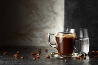 Siyah taş bir masada espresso ve bir bardak soğuk su. Boşluğu kopyala.