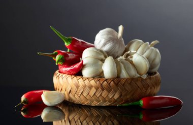 Siyah yansıtıcı arka planda sarımsak soğanları ve kırmızı biberler..