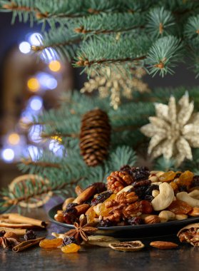 Noel baharatları, çeşitli fındıklar, kuru üzümler ve mutfak masasındaki kuru narenciye dilimleri. Noel ağacı dalları ve kurumuş meyvelerle dolu durgun bir hayat.