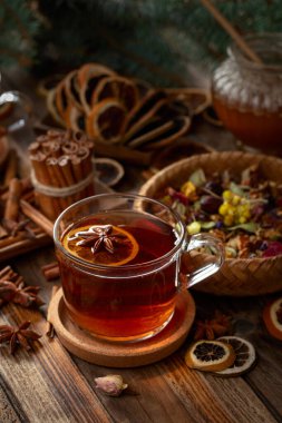 Tarçın, anason ve kuru narenciye dilimli Noel çayı. Eski ahşap bir masada malzemeli bitki çayı..