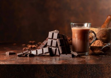 Kahverengi bir şarap masasında acı çikolata ve bir bardak kakao. Boşluğu kopyala.